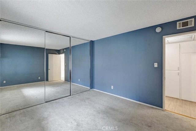 unfurnished bedroom featuring a textured ceiling, visible vents, a closet, and carpet