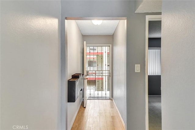 hallway featuring baseboards and light wood-style flooring