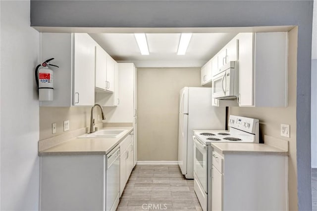kitchen with white appliances, light wood-style flooring, light countertops, a sink, and white cabinetry