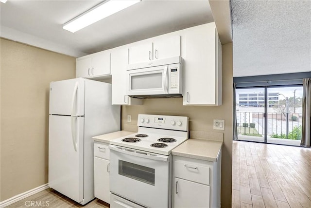 kitchen with light countertops, white appliances, light wood-style flooring, baseboards, and white cabinets