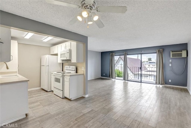 kitchen featuring white appliances, white cabinets, a sink, a ceiling fan, and a textured ceiling