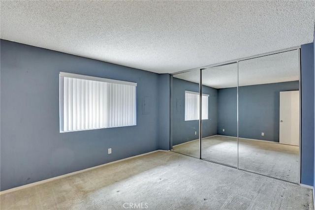 unfurnished bedroom with carpet, a textured ceiling, and a closet