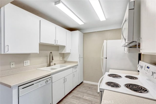 kitchen with white cabinetry, a sink, light countertops, light wood finished floors, and white appliances