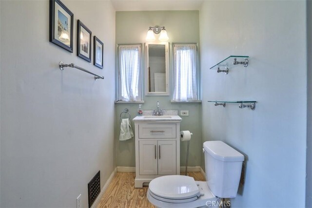 1956 E Woodlyn Rd, Pasadena, CA 91104 - half bathroom featuring toilet, visible vents, wood finished floors, and vanity