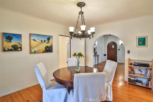 1956 E Woodlyn Rd, Pasadena, CA 91104 - dining room featuring light wood-type flooring, arched walkways, baseboards, and a chandelier