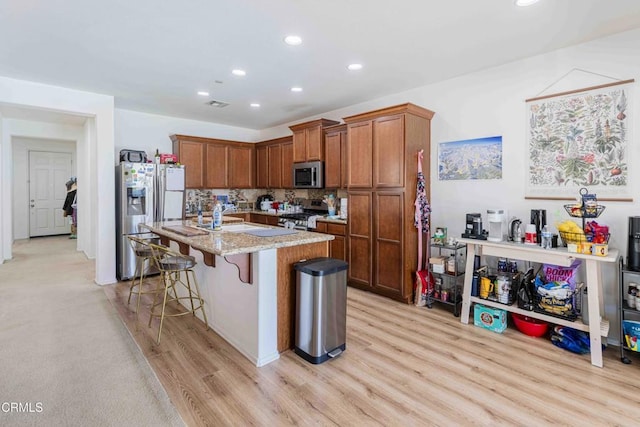 10909 Rainwater Ln, Bakersfield, CA 93306 - kitchen featuring appliances with stainless steel finishes, recessed lighting, light wood finished floors, a breakfast bar, and brown cabinets