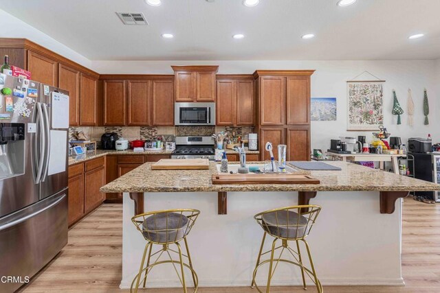 10909 Rainwater Ln, Bakersfield, CA 93306 - kitchen featuring appliances with stainless steel finishes, brown cabinets, recessed lighting, and light stone countertops