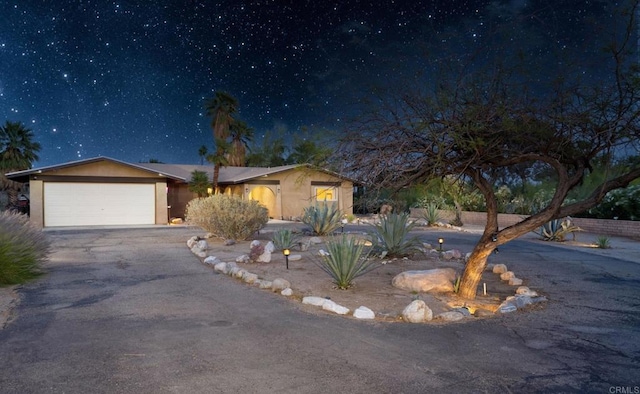 view of front of property with asphalt driveway, a garage, and stucco siding