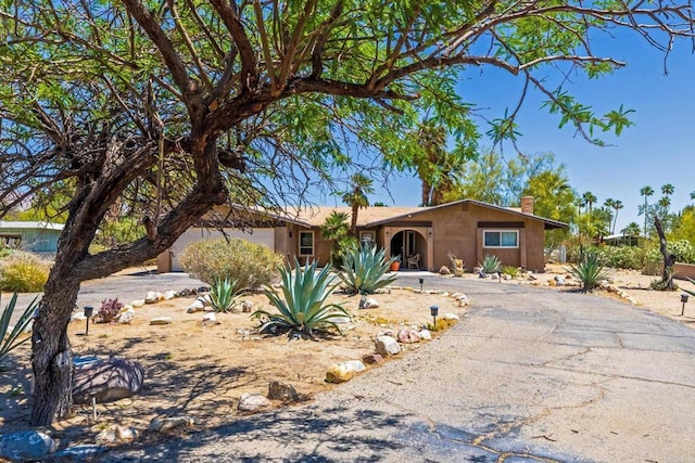 ranch-style house featuring a chimney and driveway