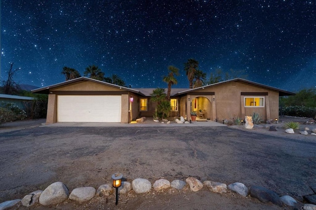 ranch-style house with stucco siding, a garage, and driveway