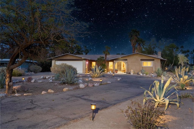 single story home featuring stucco siding, asphalt driveway, a chimney, and an attached garage