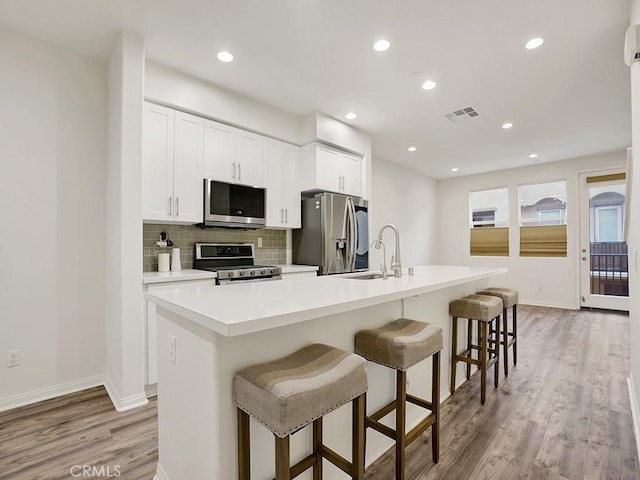 15331 Jasmine Ln Unit 105, Gardena, CA 90249 - kitchen with stainless steel appliances, light wood finished floors, an island with sink, decorative backsplash, and baseboards