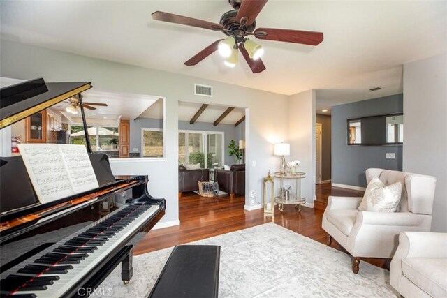 sitting room featuring wood finished floors, beamed ceiling, baseboards, visible vents, and a ceiling fan