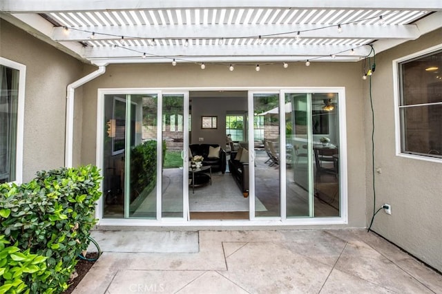 property entrance featuring a patio area, stucco siding, and a pergola