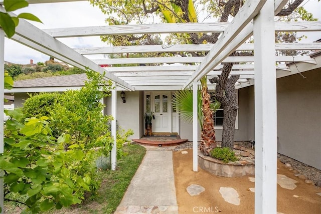 view of exterior entry with stucco siding and a pergola