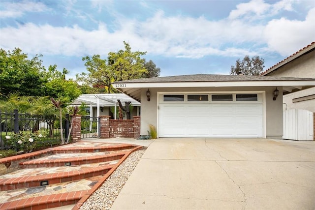 view of front of home with stucco siding, fence, a garage, concrete driveway, and a pergola
