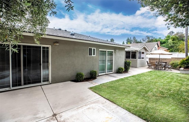 back of property with a patio, fence, stucco siding, and a yard