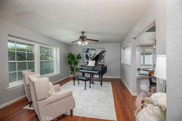 living area featuring dark wood-style flooring, a healthy amount of sunlight, ceiling fan, and visible vents