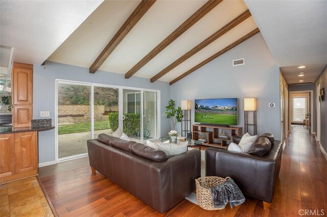 living area with beam ceiling, high vaulted ceiling, visible vents, baseboards, and wood finished floors