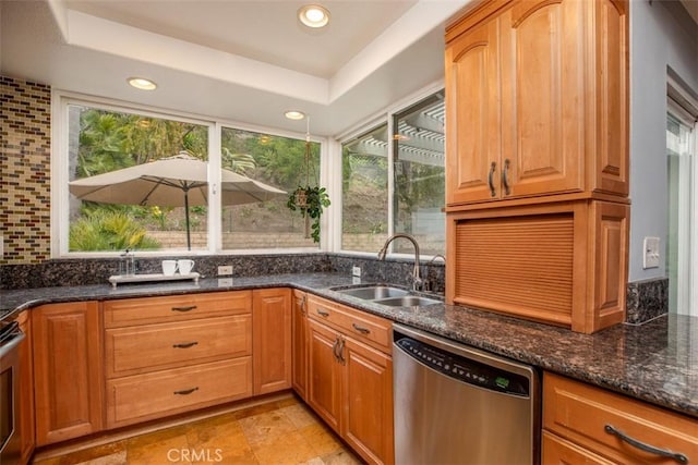 kitchen with dark stone counters, stainless steel dishwasher, recessed lighting, and a sink