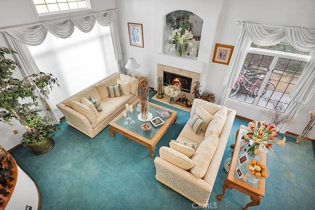 carpeted living area featuring a tile fireplace, a wealth of natural light, and baseboards