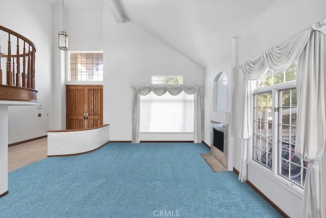 unfurnished living room with high vaulted ceiling, stairway, a fireplace with flush hearth, and carpet flooring