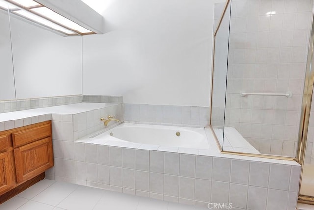 full bath featuring a tile shower, tile patterned flooring, a bath, and vanity