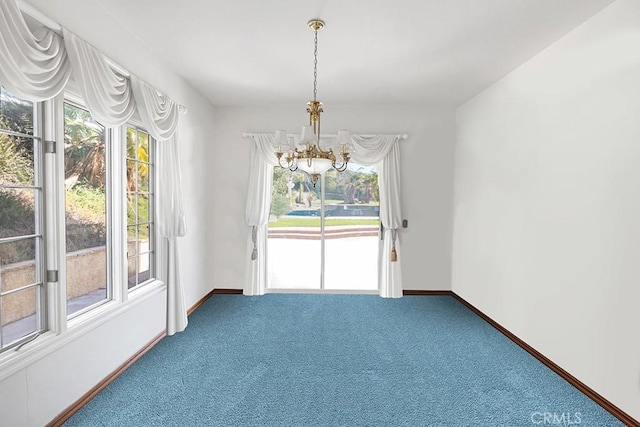 carpeted empty room featuring a chandelier and baseboards