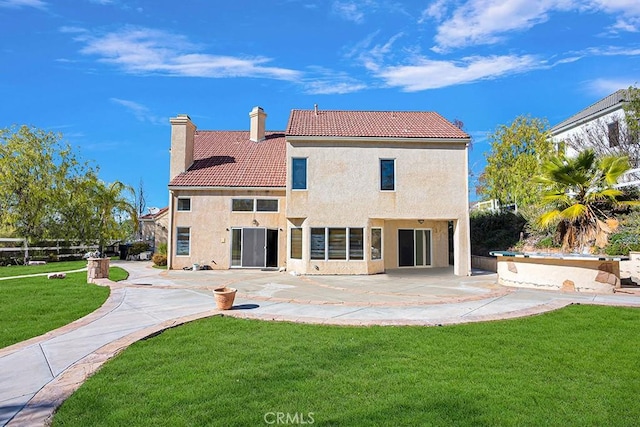 rear view of property featuring a tile roof, a patio area, a yard, a chimney, and stucco siding