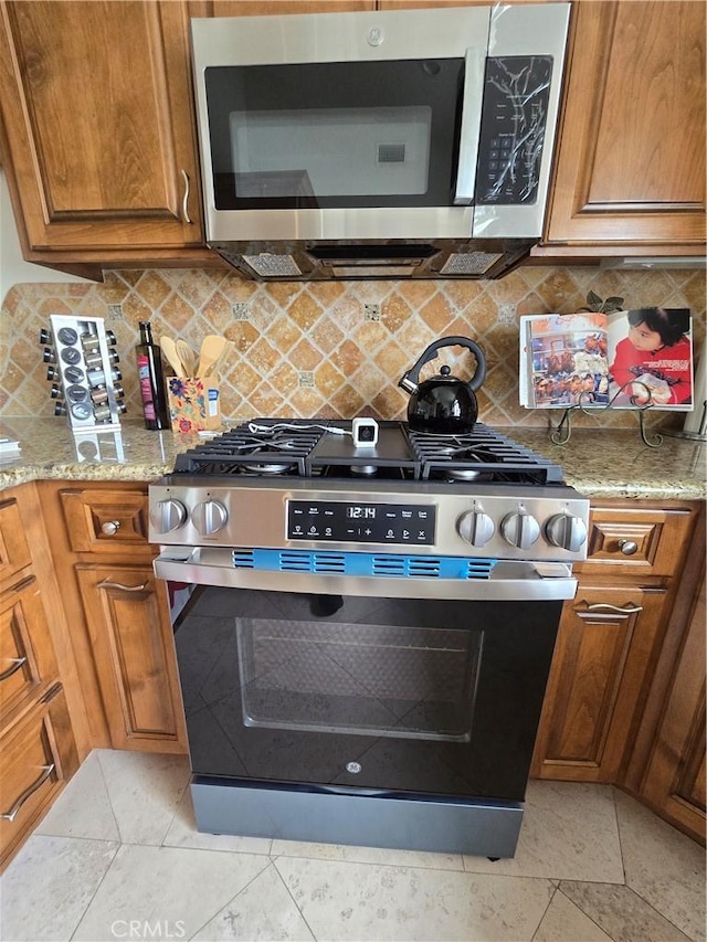 kitchen with appliances with stainless steel finishes, brown cabinets, and backsplash