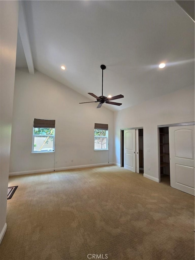 unfurnished bedroom with carpet flooring, baseboards, two closets, high vaulted ceiling, and multiple windows