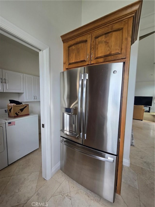 kitchen featuring baseboards, washer and dryer, stainless steel fridge with ice dispenser, and brown cabinets