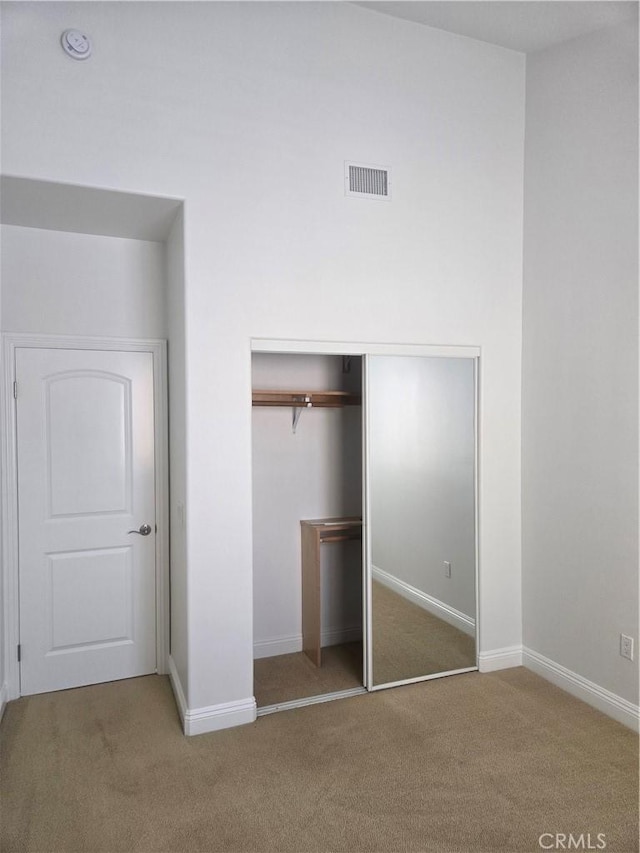 unfurnished bedroom with baseboards, visible vents, carpet floors, and a closet