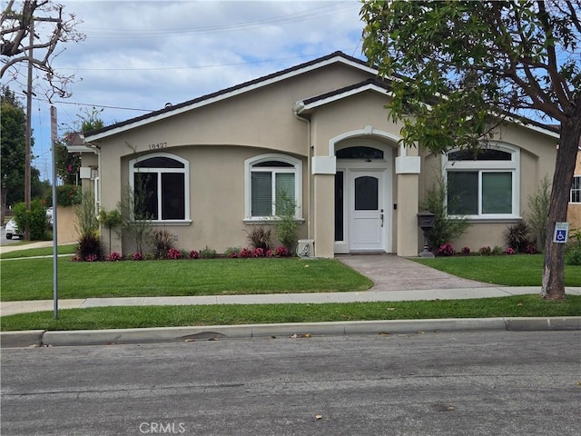 view of front of property featuring stucco siding and a front yard