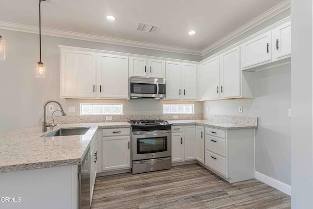 kitchen featuring stainless steel appliances, white cabinets, a sink, light wood-type flooring, and crown molding