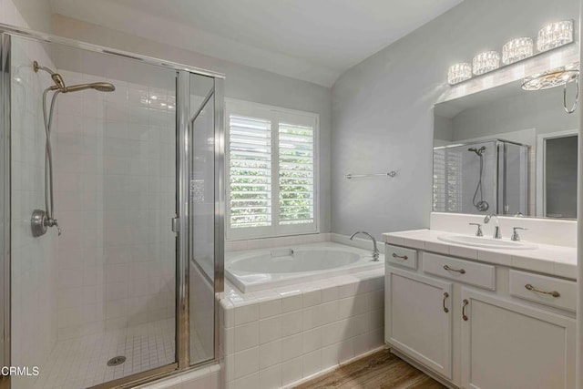 full bathroom featuring a stall shower, a garden tub, wood finished floors, and vanity
