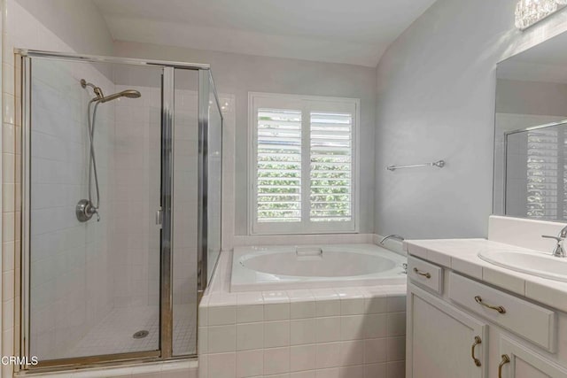 bathroom with a stall shower, a bath, and vanity