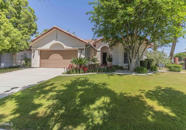 mediterranean / spanish home with a front lawn, a garage, a tiled roof, concrete driveway, and stucco siding