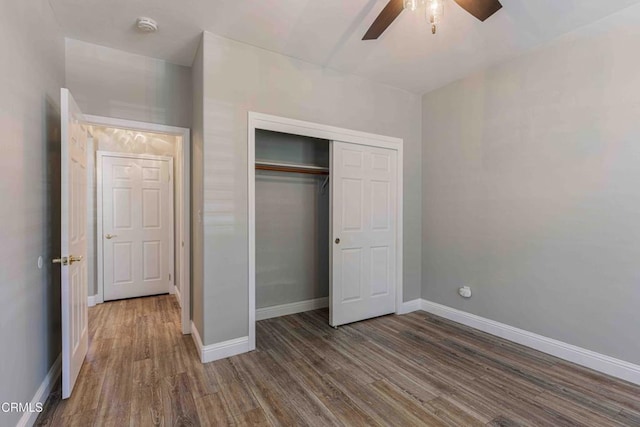 unfurnished bedroom with baseboards, wood finished floors, a ceiling fan, and a closet