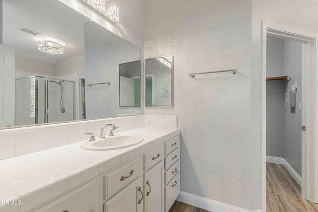 bathroom with wood finished floors, visible vents, vanity, and a stall shower