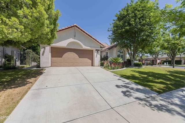 mediterranean / spanish-style home featuring stucco siding, a tiled roof, a front yard, concrete driveway, and an attached garage