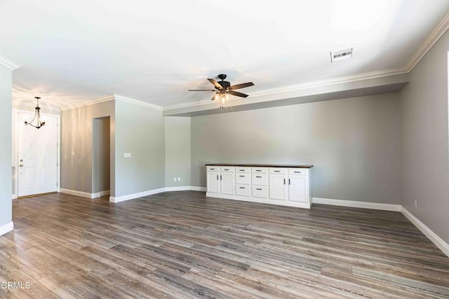 spare room with ornamental molding, ceiling fan with notable chandelier, wood finished floors, and baseboards