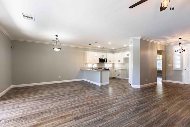 unfurnished living room featuring dark wood-style floors, crown molding, visible vents, baseboards, and ceiling fan with notable chandelier