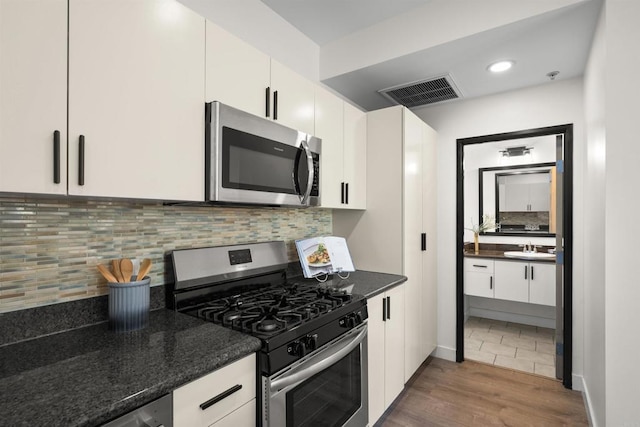 1551 4th Ave Unit 611, San Diego, CA 92101 - kitchen with a sink, stainless steel appliances, white cabinetry, wood finished floors, and visible vents