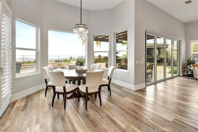 dining area featuring visible vents, baseboards, an inviting chandelier, and light wood finished floors