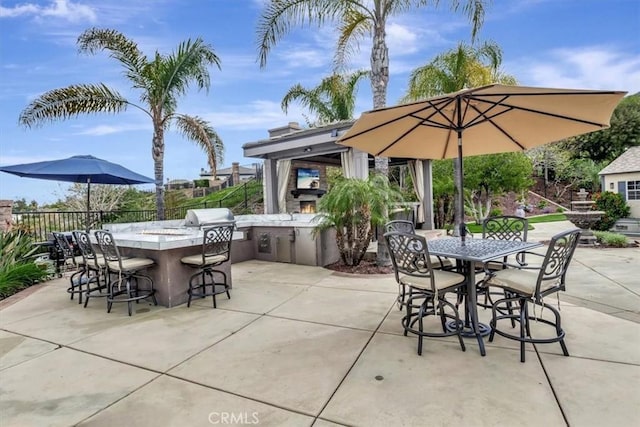 view of patio with fence, outdoor wet bar, and exterior kitchen