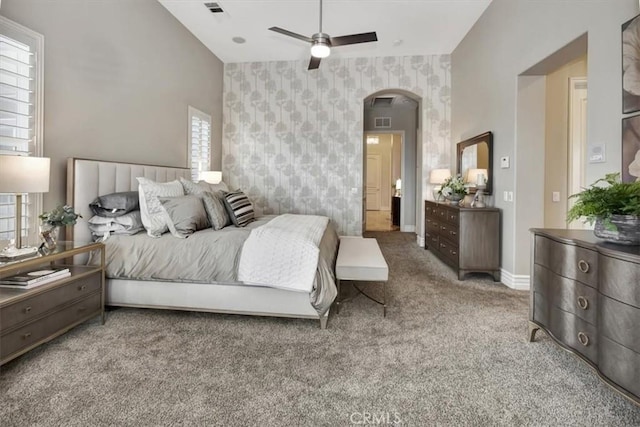 bedroom with visible vents, baseboards, wallpapered walls, arched walkways, and carpet