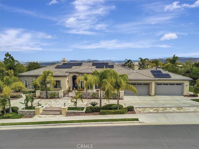 view of front of property featuring a garage, roof mounted solar panels, driveway, and a tile roof