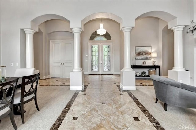 entryway featuring arched walkways, baseboards, french doors, and marble finish floor