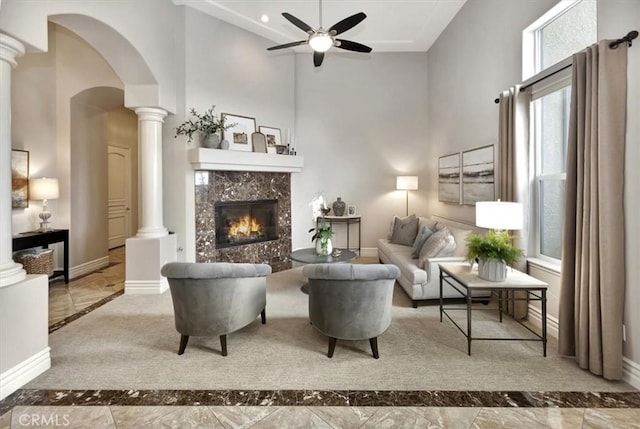 living area with baseboards, a ceiling fan, a high ceiling, and a premium fireplace